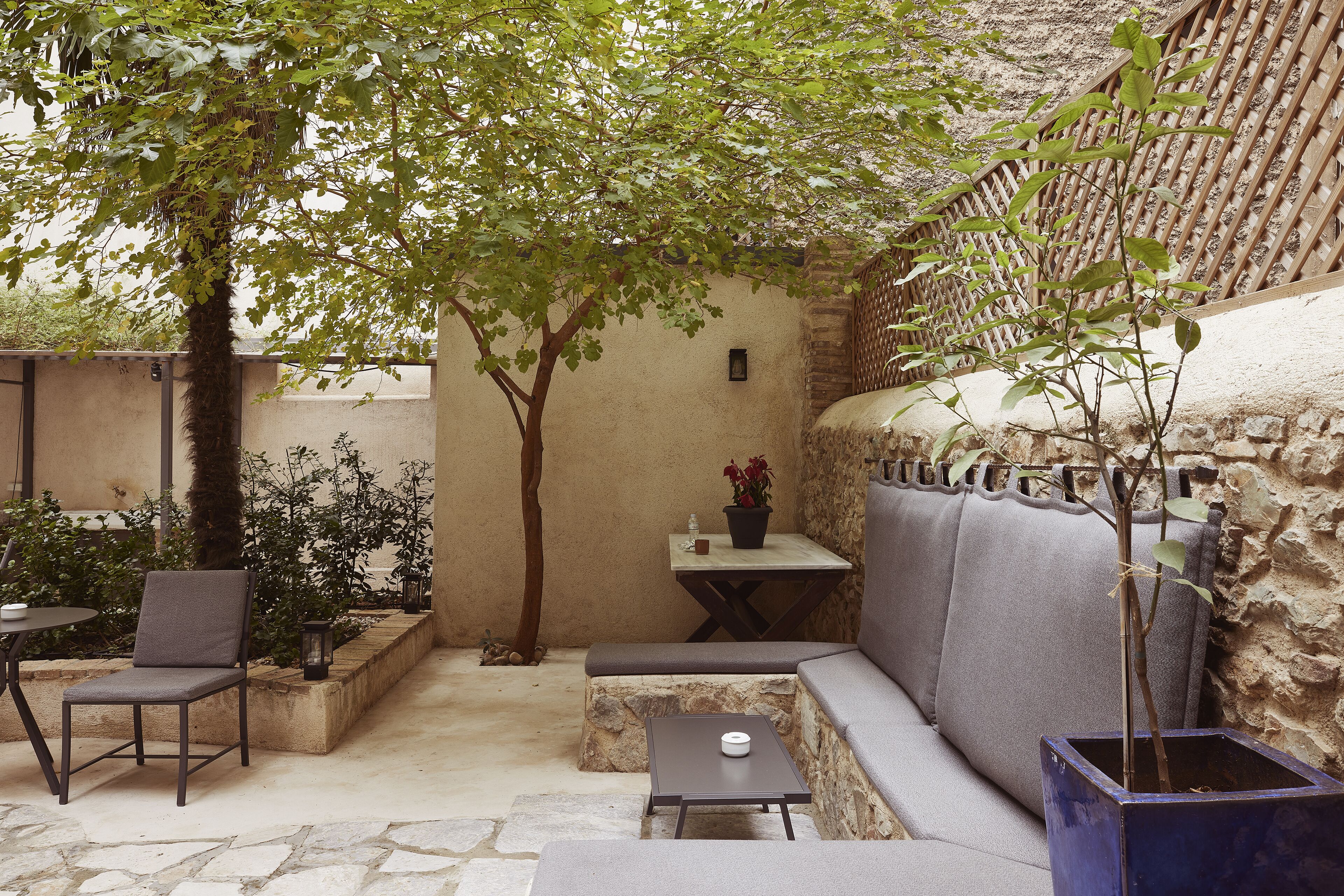 Un espace extérieur accueillant, aménagé avec un banc rembourré, une petite table et une chaise.