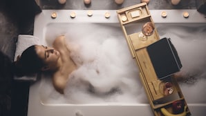 A person in a bathtub with candles and a tray of items. - Bohemian Suites Athens - Maison Hotel Adults Only (Athens)
