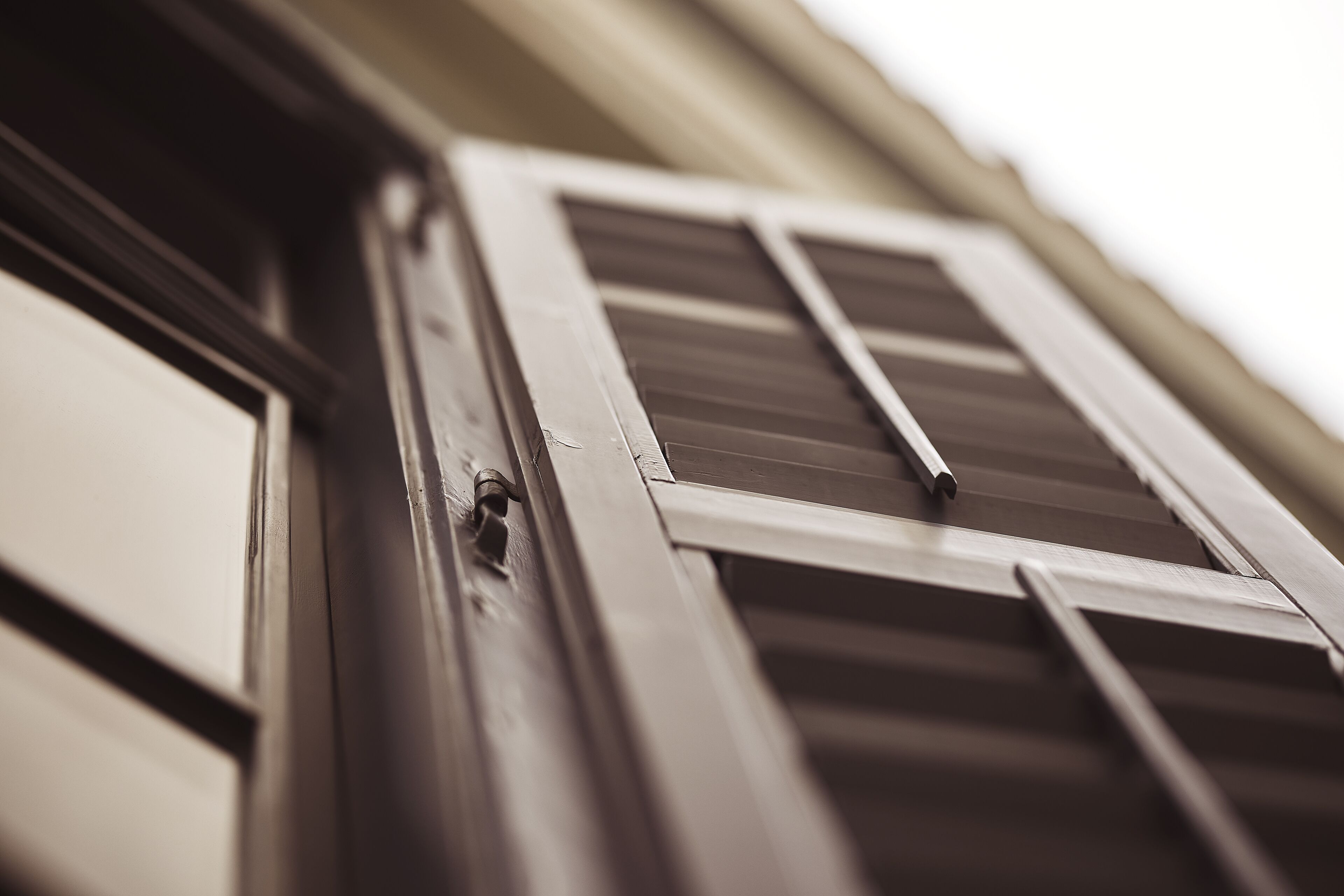 A close-up of a window with wooden shutters and a metal latch.
