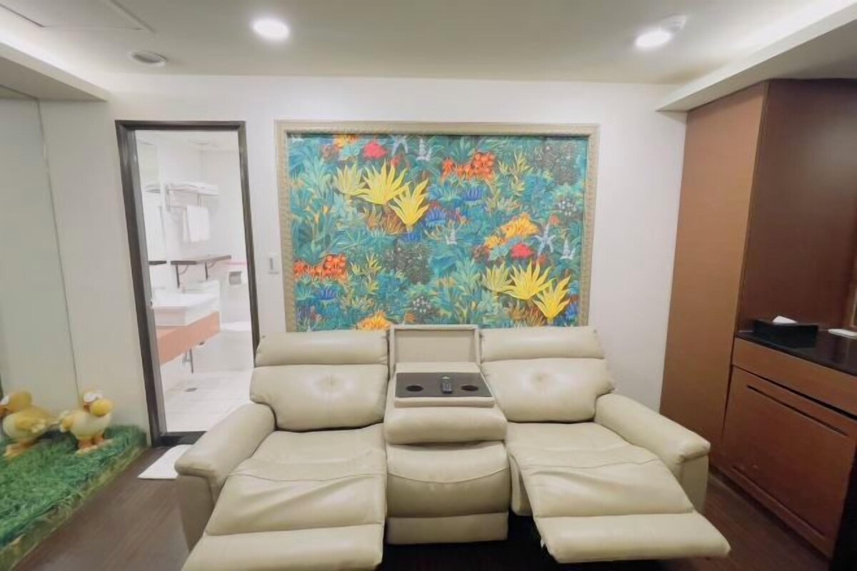 Una habitación con sofá color beige, una mesita y un mural de pared colorido.