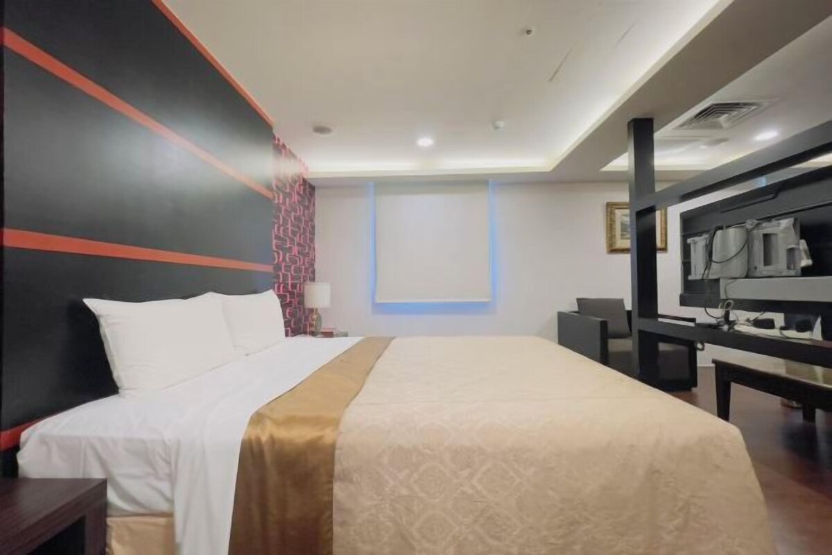 Una habitación de hotel con cama, escritorio, silla y televisión.