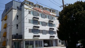 Un hotel de varios pisos con un letrero que dice "HERA HOTEL" y un estacionamiento debajo.