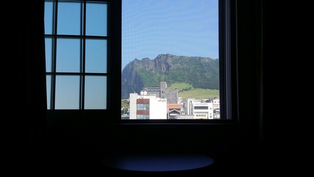 Una ventana con vistas a una montaña y edificios.