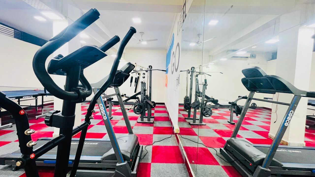 A gym with cardio machines, weight machines, and a red and white checkered floor.