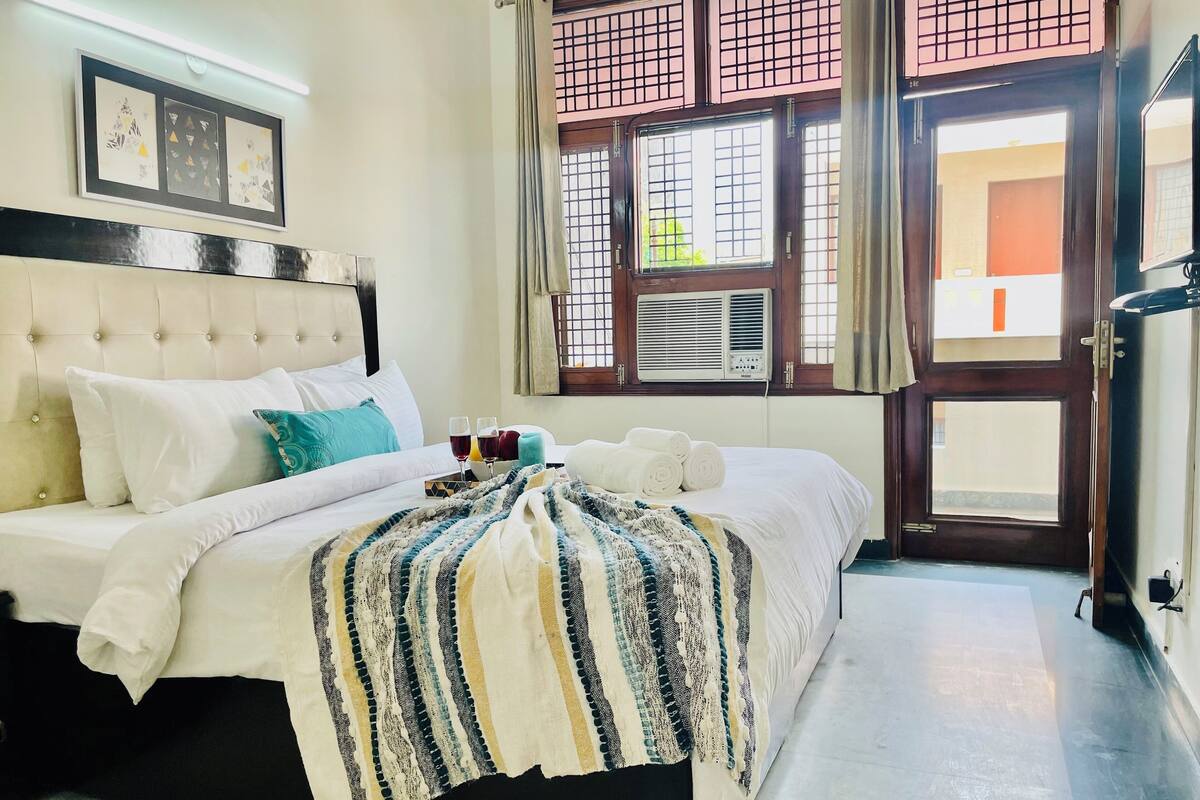 Una habitación de hotel con una cama, un ventanal con vistas y un aire acondicionado.