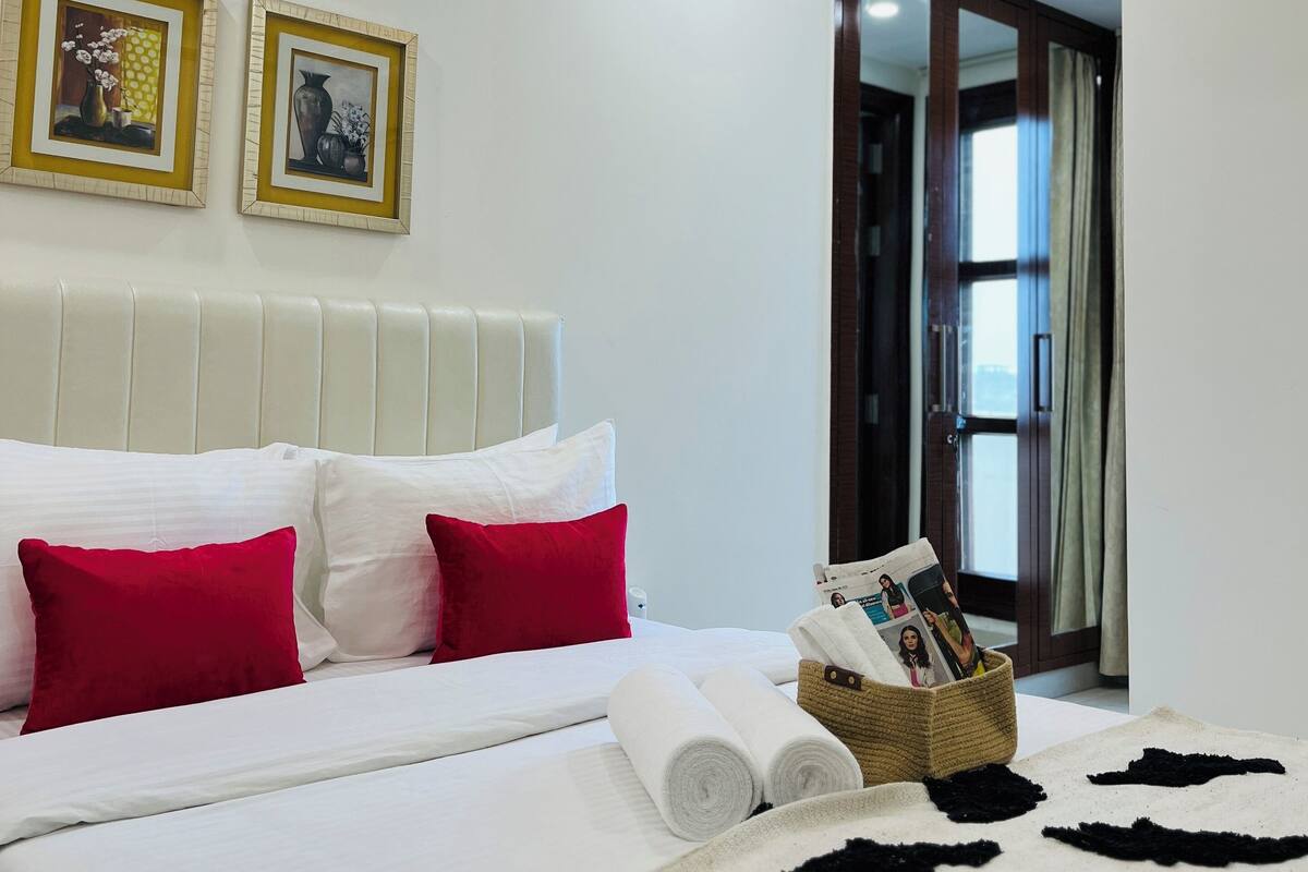 Una habitación de hotel con una cama, almohadas, una colcha y dos cuadros en la pared.