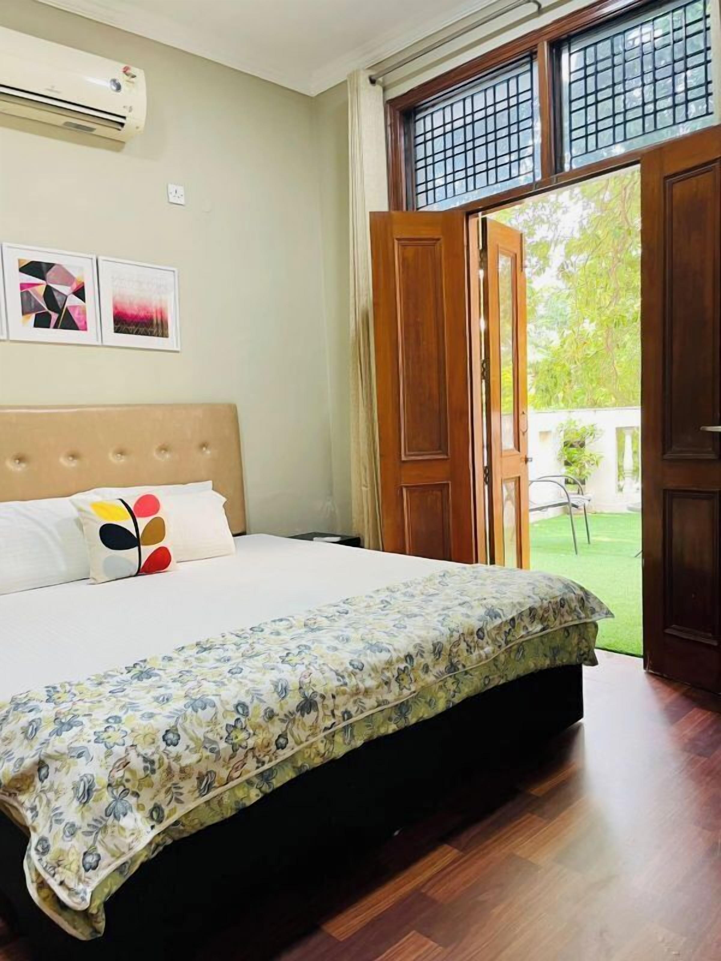 A bedroom with a bed, a window, and a door leading to a garden.