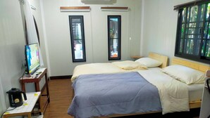 A bedroom with a bed, a TV, a coffee maker, and a window with a view. - Wasuthan Garden House (Nong Khai)