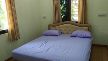 Una cama individual con cabecera, dos almohadas y una ventana con cortinas.