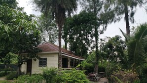 A single-story house with a sloped roof, surrounded by lush greenery and trees. - Wasuthan Garden House (Nong Khai)