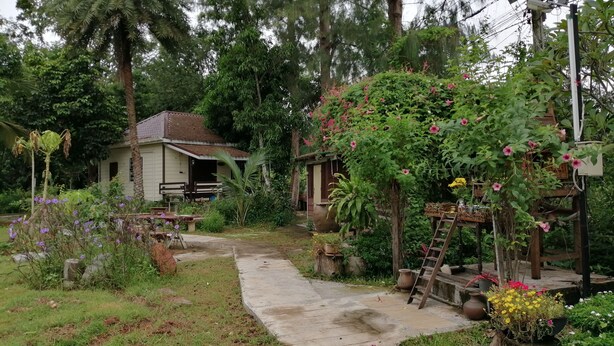 A garden with a pathway leading to a house with a porch. - Wasuthan Garden House (Nong Khai)