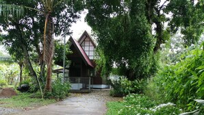A traditional house with a sloped roof, surrounded by lush greenery and a concrete pathway leading to the entrance. - Wasuthan Garden House (Nong Khai)