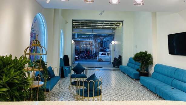 A modern lobby with a seating area, a surfboard decoration, and a view into the parking garage. - Tea Leaf Hotel (Cam Ly - Da Lat)