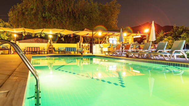 A swimming pool with lounge chairs and umbrellas, surrounded by trees and a mountain in the background. - Ada Apart Hotel (Ortaca)