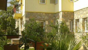 A yellow building with stone accents, a welcome sign, and a well-maintained lawn. - Ada Apart Hotel (Ortaca)