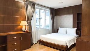 Une chambre à coucher avec un lit en bois, une table de chevet avec une lampe et une grande fenêtre avec des rideaux.