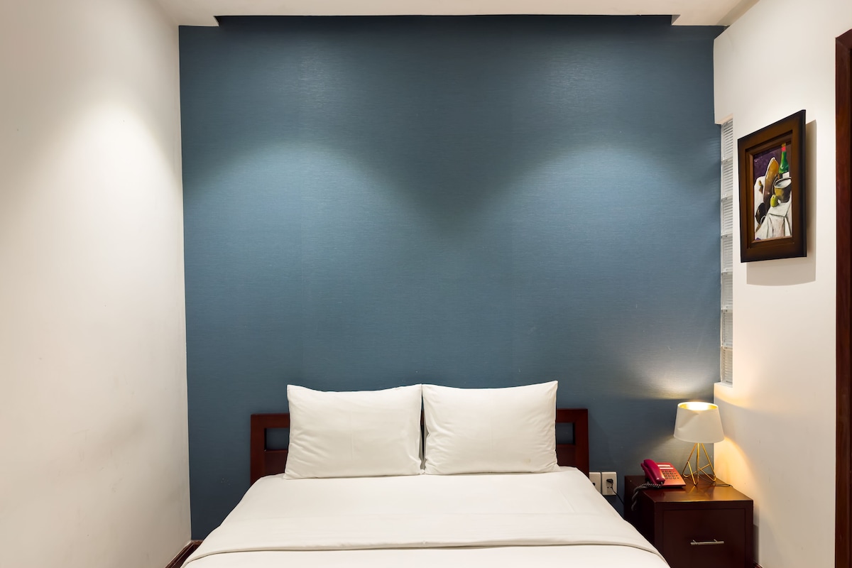 Une chambre d’hôtel avec un lit, une table de chevet, une lampe et un tableau au mur.