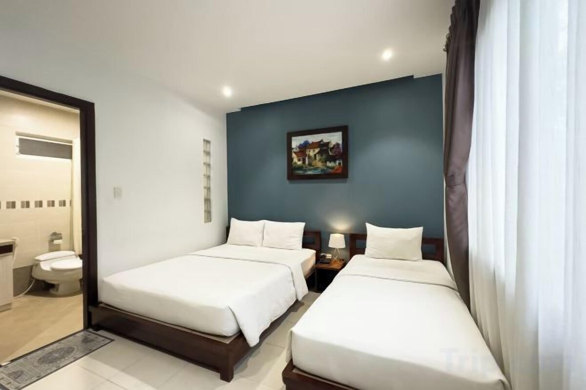 Une chambre d’hôtel avec deux lits, une salle de bain et un tableau au mur.