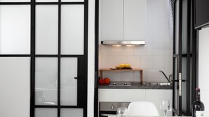 Una cocina moderna con encimera blanca, horno integrado y una botella de vino sobre la mesa.