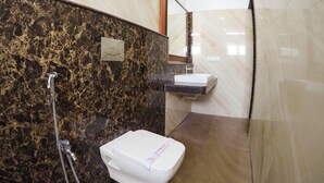 A bathroom with a marble vanity, a toilet, and a shower area. - Hotel Maadhini (Nagercoil)