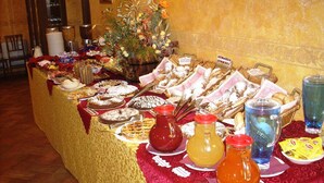 Une table de buffet proposant divers plats, notamment des pâtisseries et des desserts, ainsi qu’un choix de boissons.
