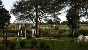 Ein Garten mit Schaukel, ordentlich geschnittenen Büschen und einem großen Baum.