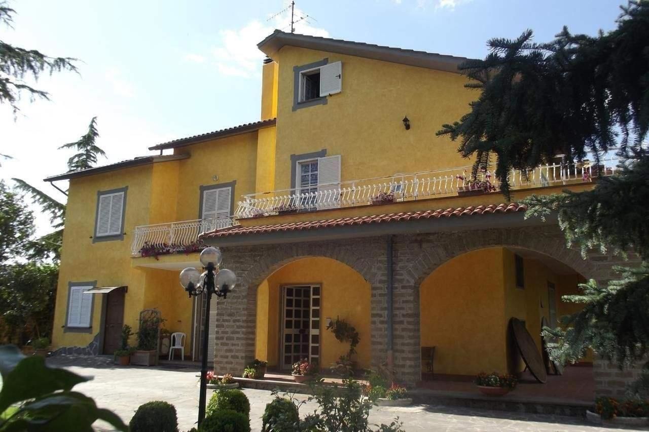 A yellow building with a balcony, arched doorways, and a tiled roof.
