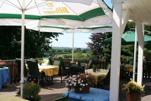 An outdoor patio with tables and chairs, umbrellas, and potted plants. - Hotel Wuppertaler Hof (Remscheid)