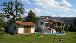 A two-story house with a swimming pool and a swing set in the yard. - Lucrezia e Cesare Borgia (Serrapetrona)