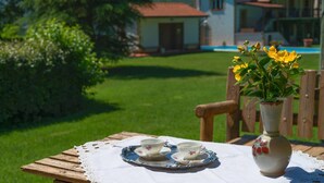 A wooden table with a lace tablecloth, two cups, and a vase with yellow flowers. - Lucrezia e Cesare Borgia (Serrapetrona)