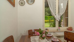A dining table with a vase of flowers, a lace tablecloth, and a window with curtains. - Lucrezia e Cesare Borgia (Serrapetrona)