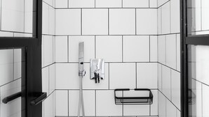 A modern bathroom with white tiled walls, a showerhead, a handheld shower, and a towel rack. - Athens View Loft - 04 (Athens)