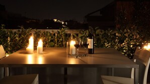 A table set for dining with candles, wine glasses, and a bottle, surrounded by greenery. - Athens View Loft - 04 (Athens)