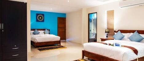 A modern bedroom with two beds, a wardrobe, and a blue accent wall.