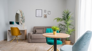 A modern living room with a sofa, a round table with a plant, a yellow chair, and a large mirror. - B&B Pontenuovo Bed (Naples)