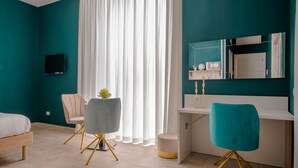 A modern bedroom with teal walls, a white desk, a grey chair, a white bed, and a TV mounted on the wall. - B&B Pontenuovo Bed (Naples)