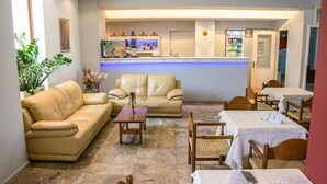 Un hall d’hôtel comprenant un comptoir d’accueil, des canapés en cuir, des tables et des chaises en bois.