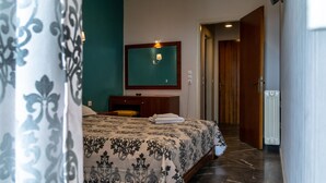 Une chambre d’hôtel comprenant un lit, un bureau, un miroir et une porte donnant sur une autre pièce.