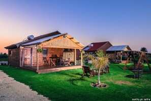 Un chalet rustique avec une façade en bois, une véranda dotée de meubles d’extérieur et un petit jardin.