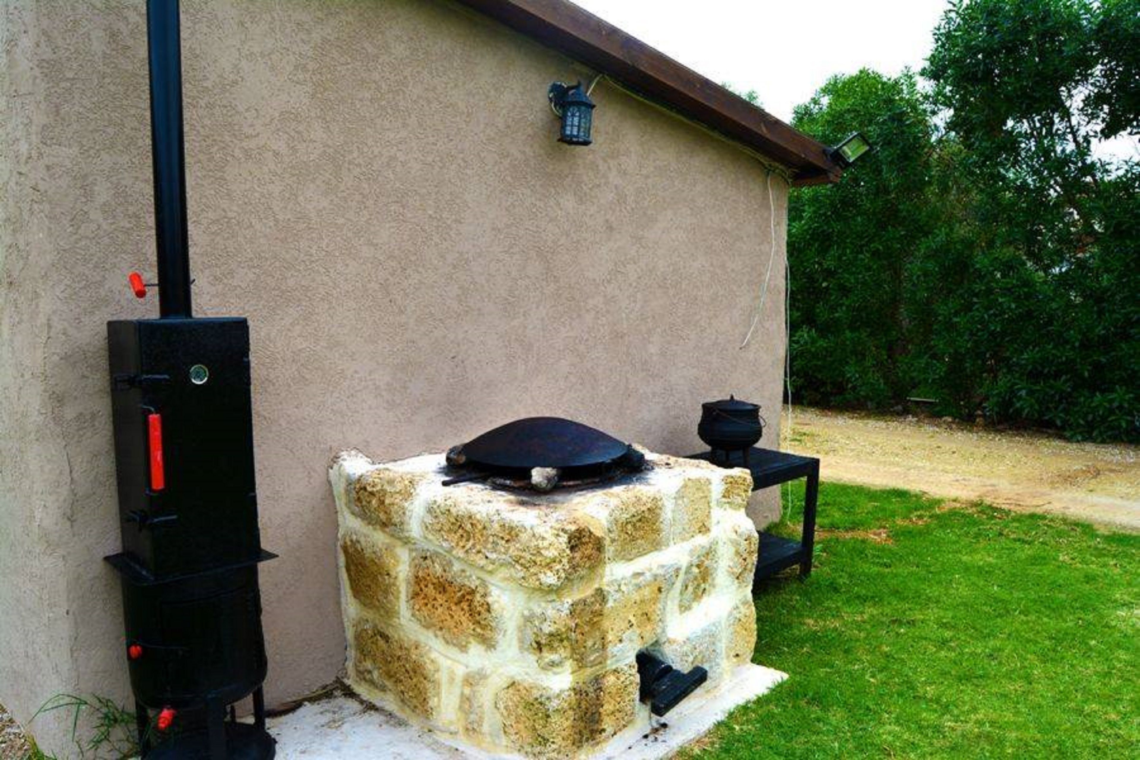 Un four extérieur en pierre, doté d’une cheminée, avec une grille noire sur le dessus et une petite table à côté.