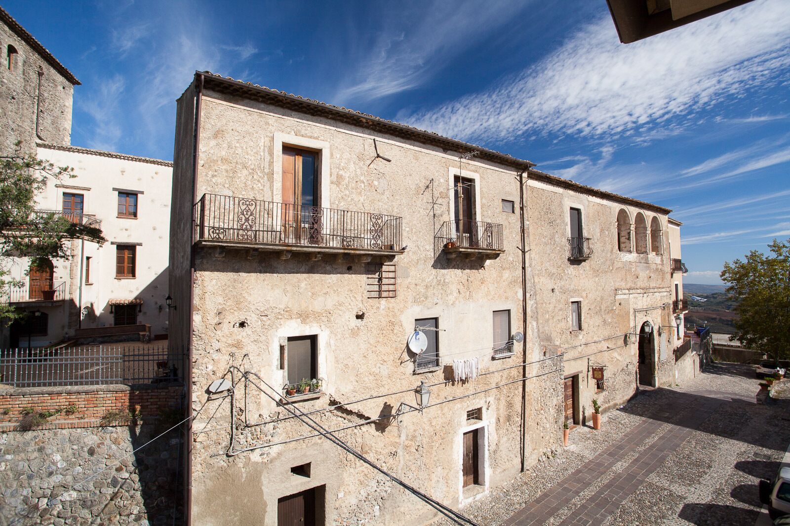 A historic building with multiple balconies, a stone facade, and a cobblestone street.