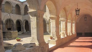 An interior courtyard with stone arches, a tiled floor, and hanging lanterns. - Castello di Altomonte (Altomonte)