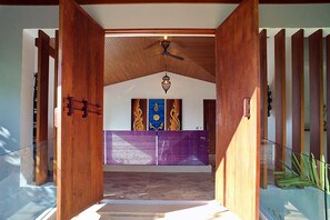 A wooden interior with a ceiling fan, a purple altar, and a wooden door frame. - Luxury Villa Crystal Blue (Koh Samui)