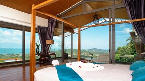 Un dormitorio con una cama grande, vistas al océano y techo de madera.