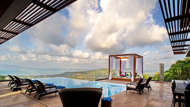 Un área junto a la piscina con sillas de descanso, un jacuzzi y vistas al mar.
