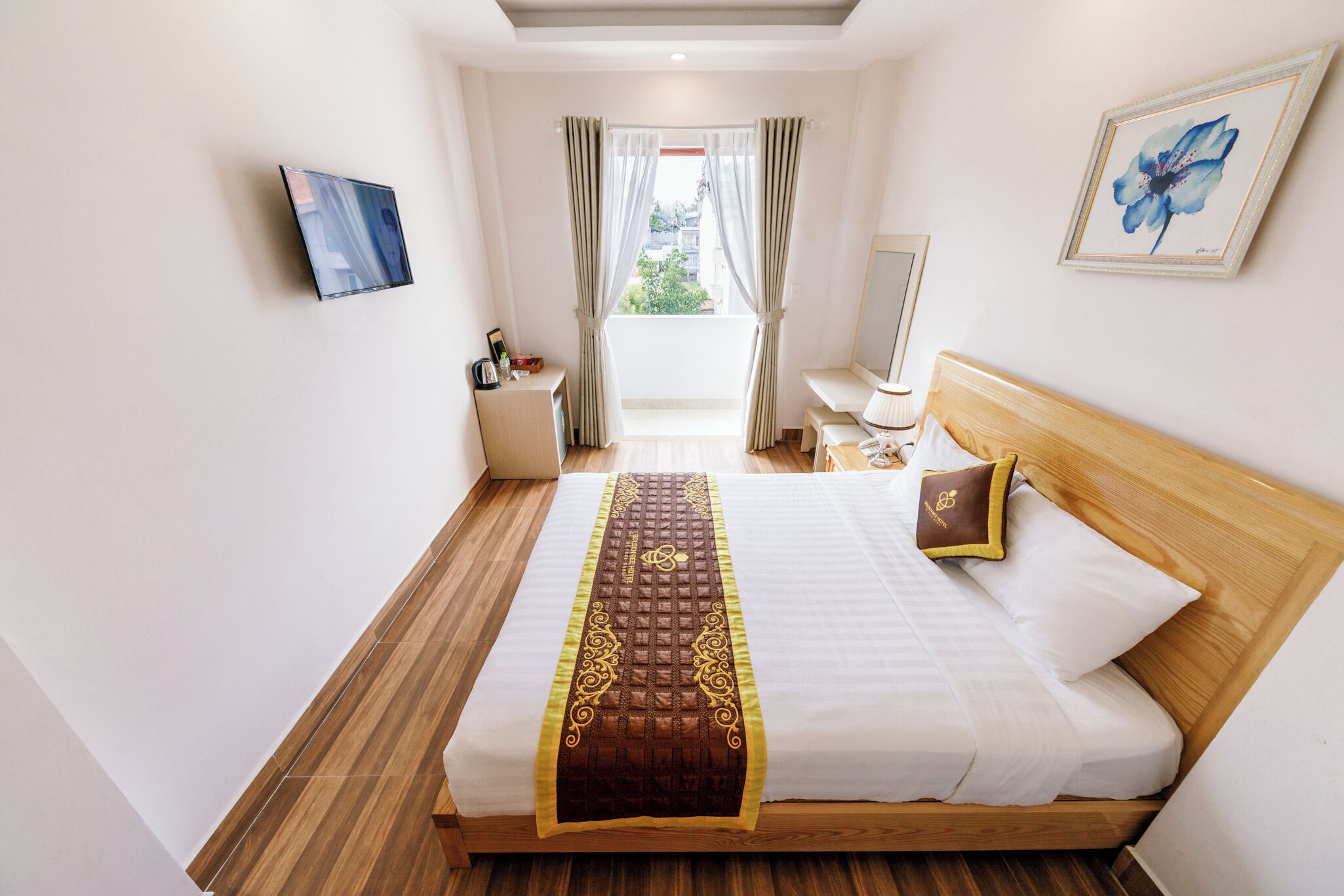 A hotel room with a wooden bed, a view through a window, a desk, and a chair.