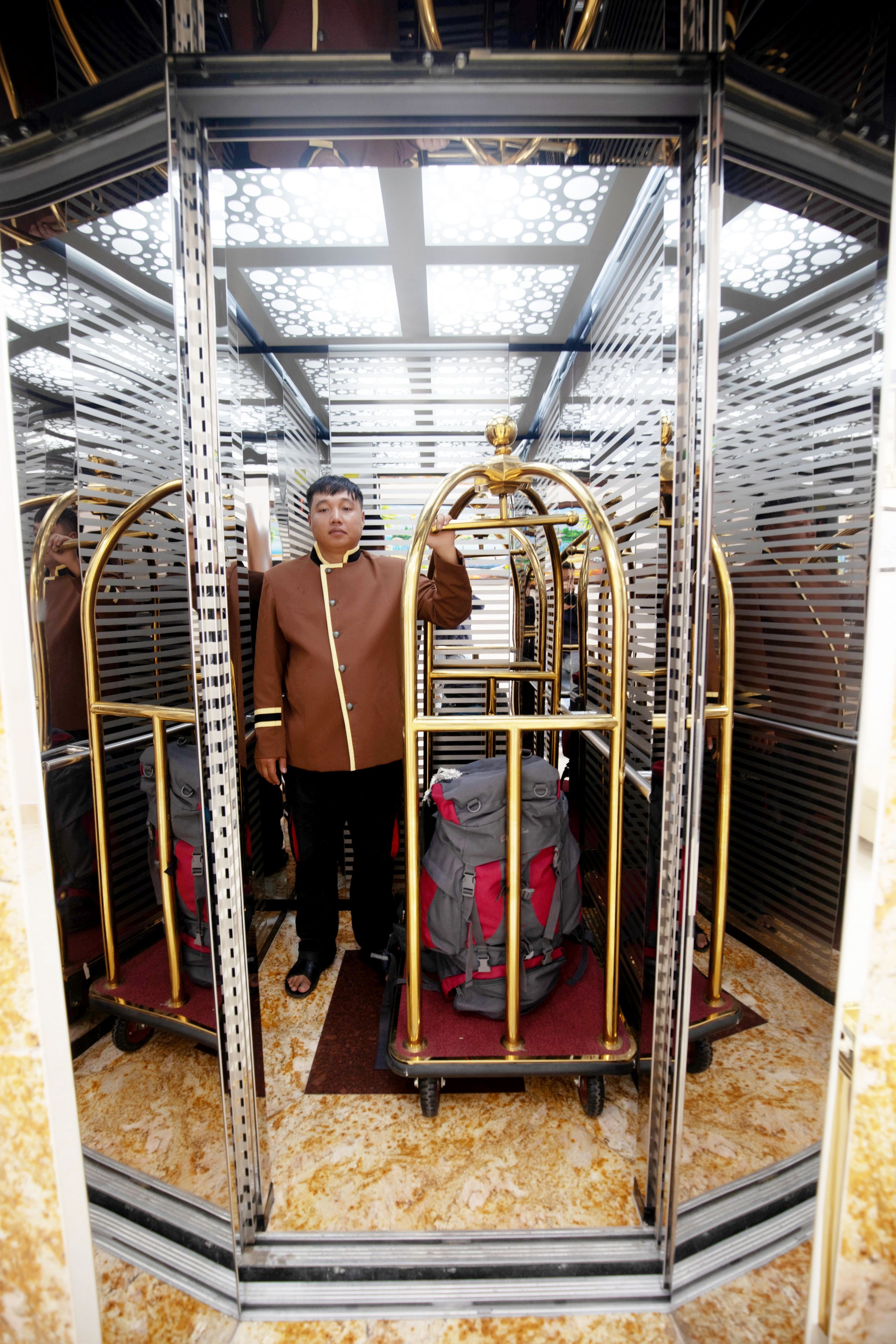 A man standing in a compartment with metal railings and a ceiling with circular patterns.
