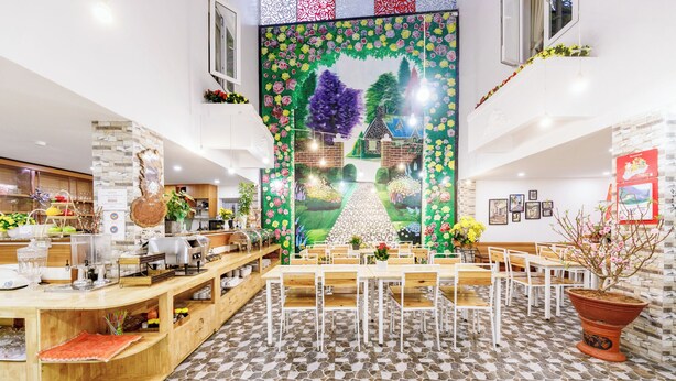 Een restaurant met een centraal muurschildering, houten tafels en een vloer van stenen tegels.