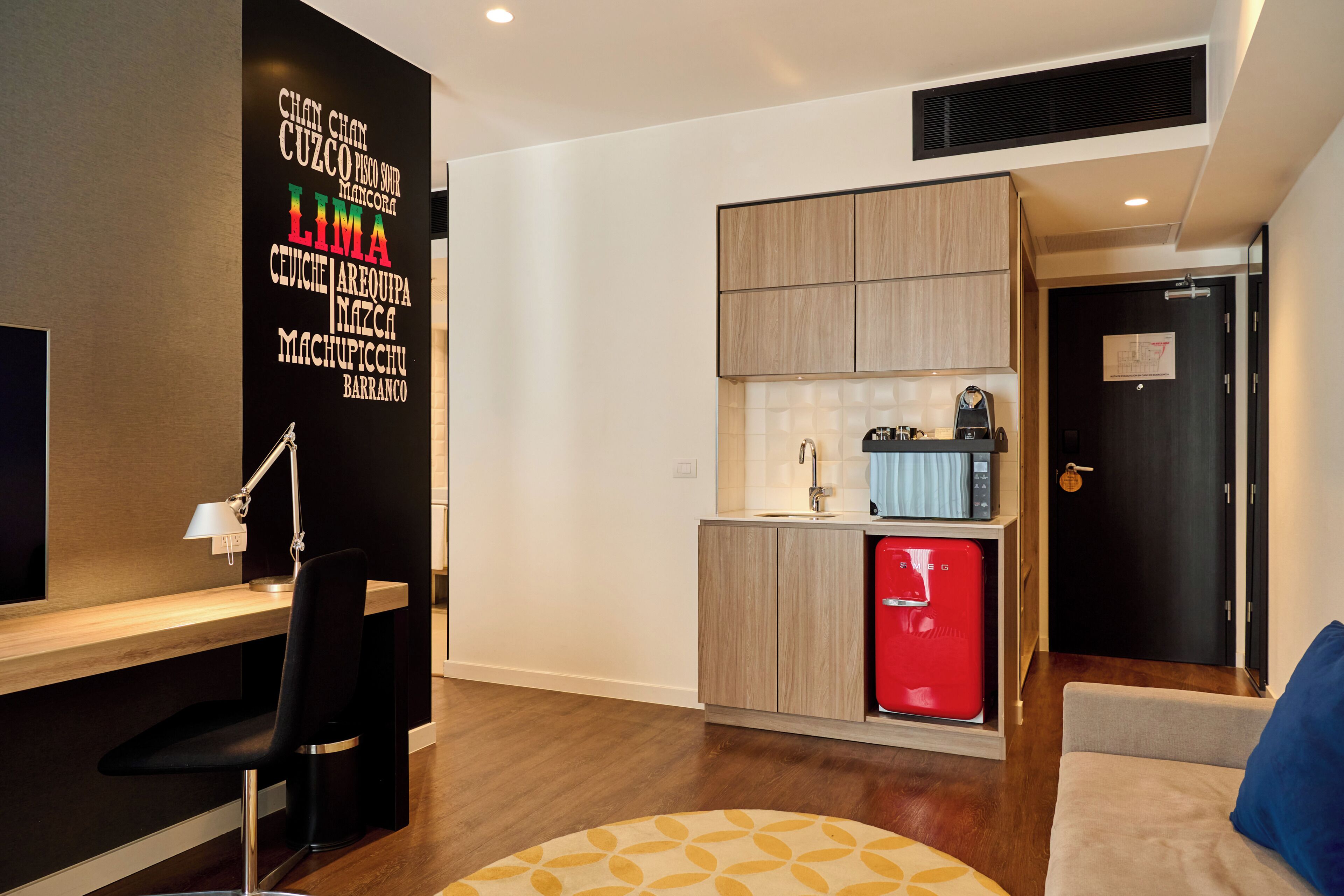 A modern kitchen with a red refrigerator, a wooden cabinet, and a black countertop.