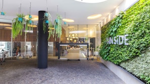 A modern indoor space with a green wall, hanging plants, and a central pillar.